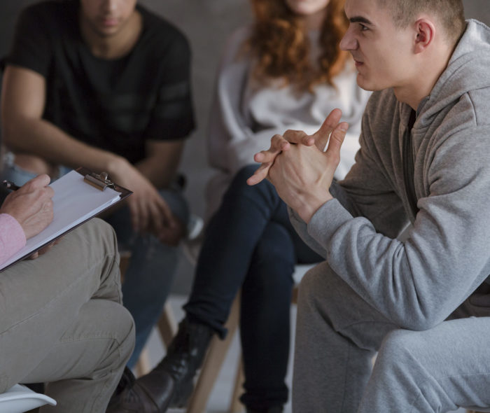A nervous teenage boy sitting in front of a therapist