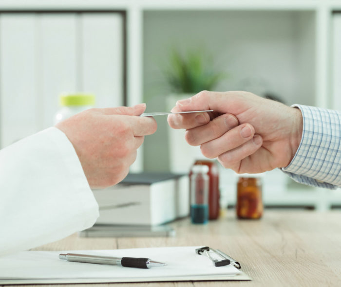 Doctor taking medical insurance card from patient