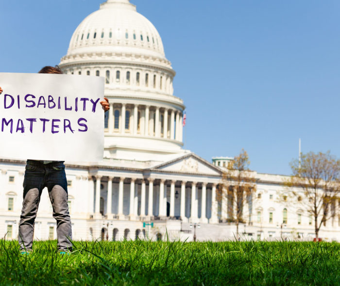 Protester boy holding sign disability matters hiding face