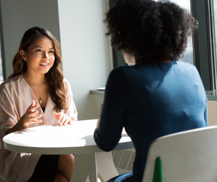 two women sitting at a table and talking