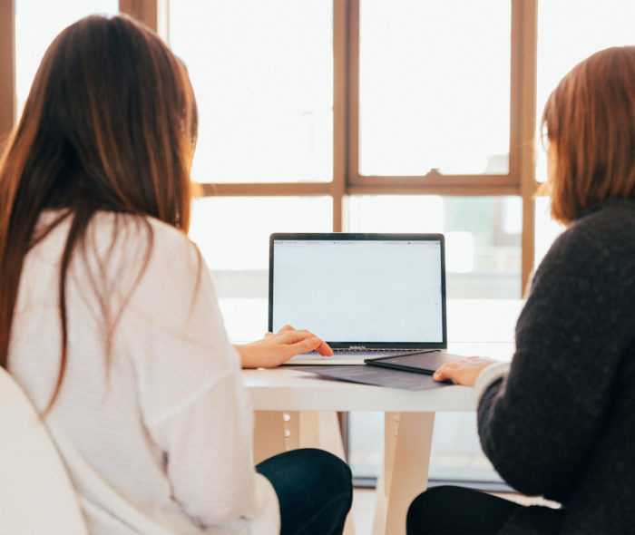 two people sitting at a laptop